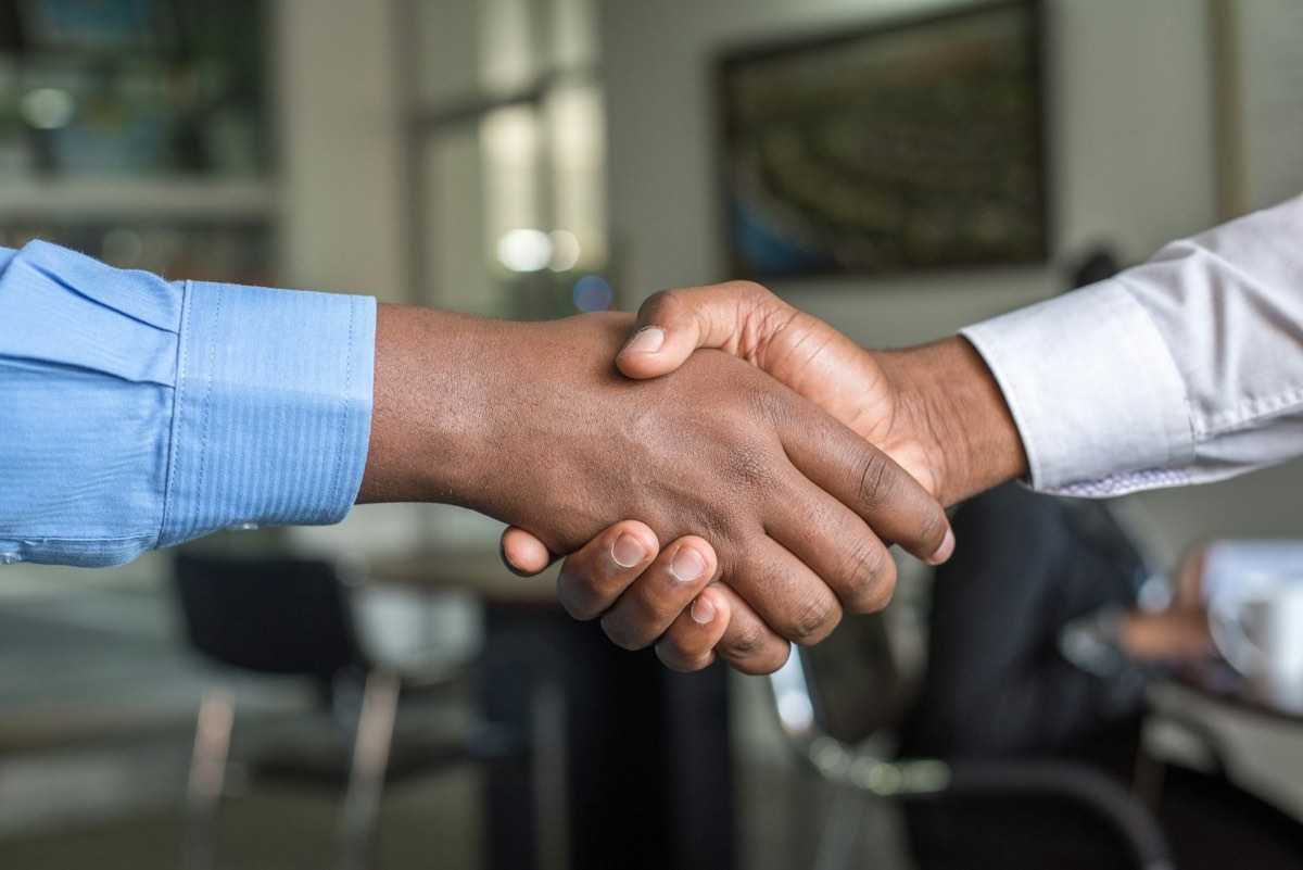 Close-up of two people shaking hands in an office.